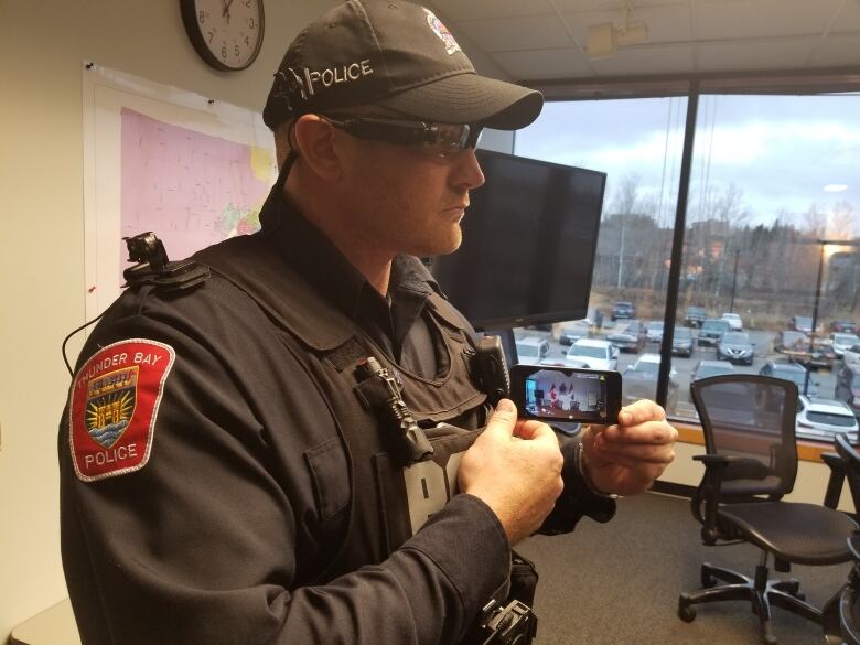 A side profile of a male police officer wearing sunglasses and a ball cap