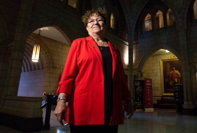 Senator Yvonne Boyer poses for a photo in the foyer of the Senate on Parliament Hill in Ottawa. She wears a red blazer and a black shirt. 