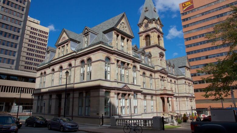 A view of the tall, beige city hall as seen from an angle. The stone building has a large clock tower in the centre