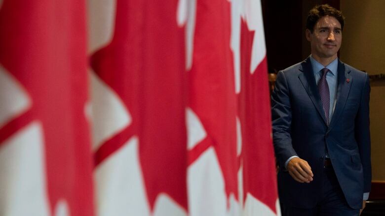 Trudeau stands next to a Canadian flag