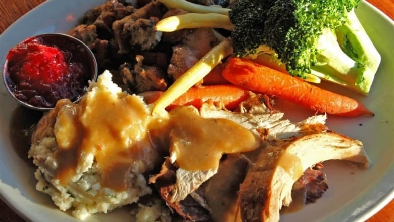 A plate of food including turkey, stuffing, broccoli, carrots and cranberry sauce.