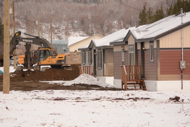 Large machinery in front of new homes in Telegraph Creek.