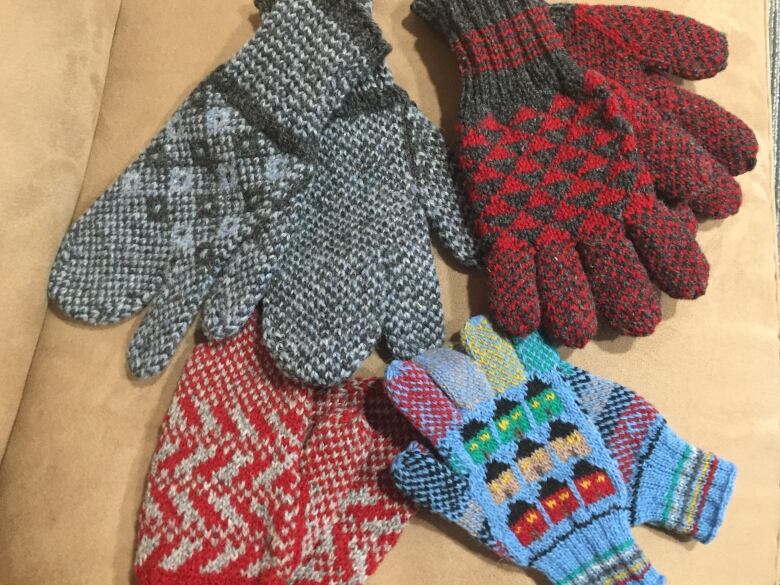 Four pairs of colourful mittens on a surface