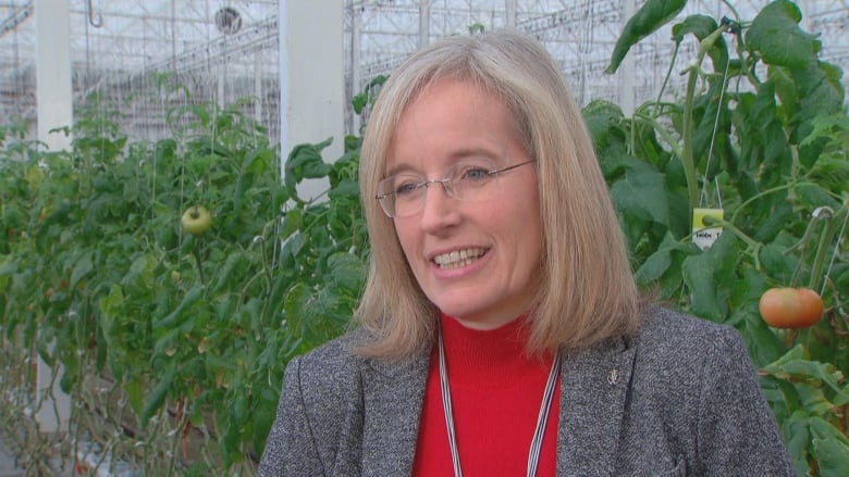 A white woman is seen in a greenhouse.