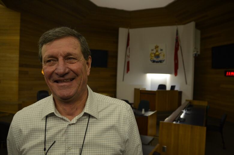 Smiling middle aged man with short brown hair stands in a city council chamber