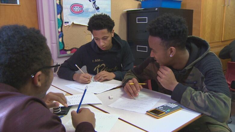 A group of people sitting at a desk working