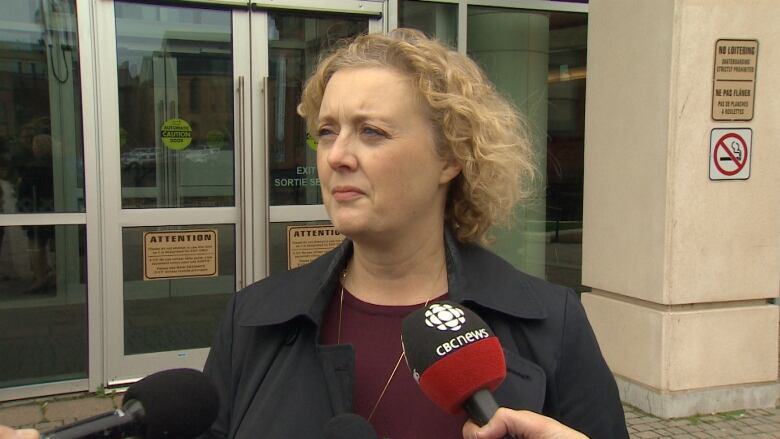 A woman with blond hair with a CBC-branded microphone in front of her