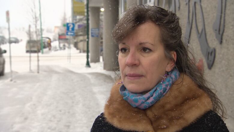 A woman stands on a city sidewalk in winter.