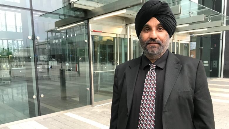 A Sikh man wearing a black turban smiles for the camera.