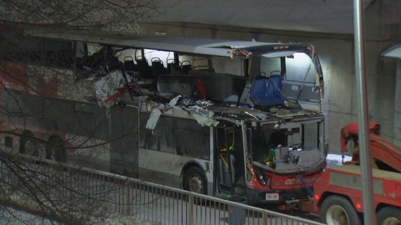 A tow truck attached to a damaged OC Transpo double decker bus. 