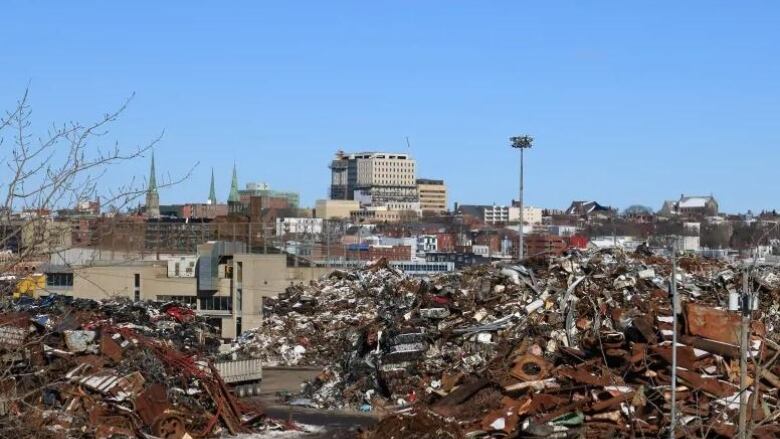 Piles of rusty metal in foreground, buildings in background