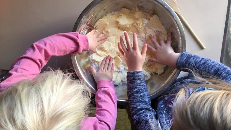 An overhead shot of two girls mixing food in a bowl.