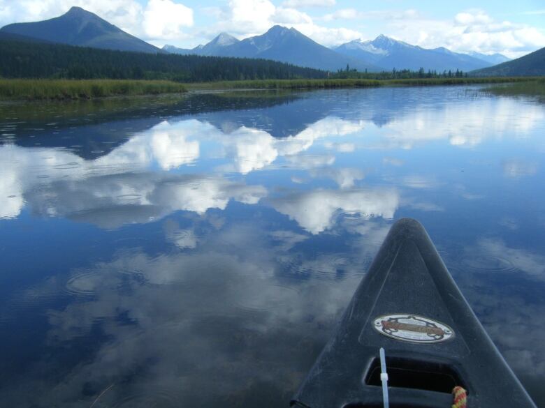 A canoe overlooking the lake and the mountains and hills in the horizon