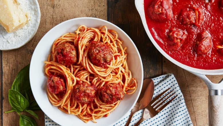 Overhead shot of a bowl of spaghetti and meatballs next to a pot of the sauce. 