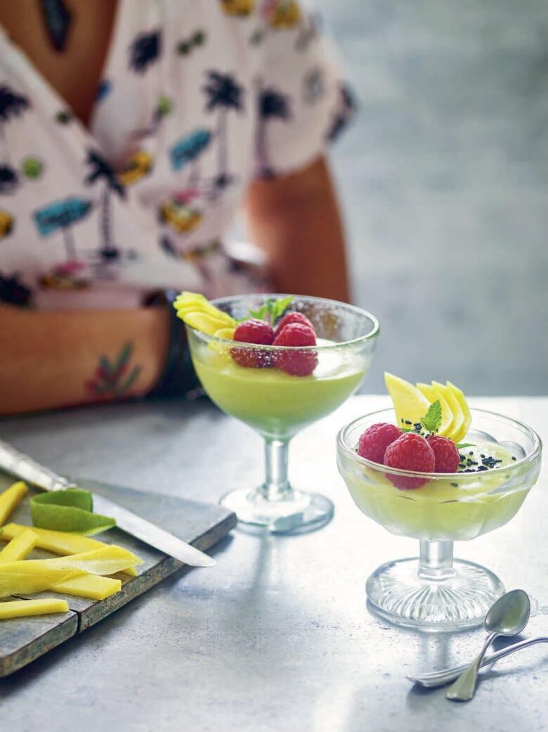 Coupe glasses filled with mango mousse on a countertop.