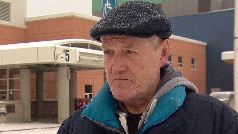 Yukon Employees Union President Steve Geick stands in front of the Whitehorse General Hospital with a black cap on. 