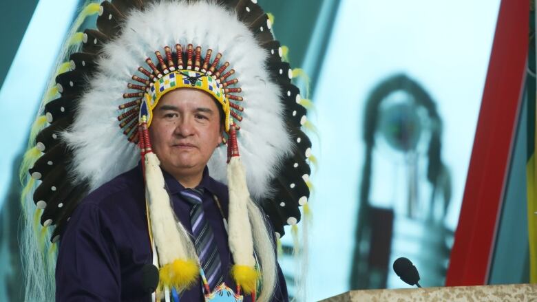 Man addresses crowd in Indigenous attire