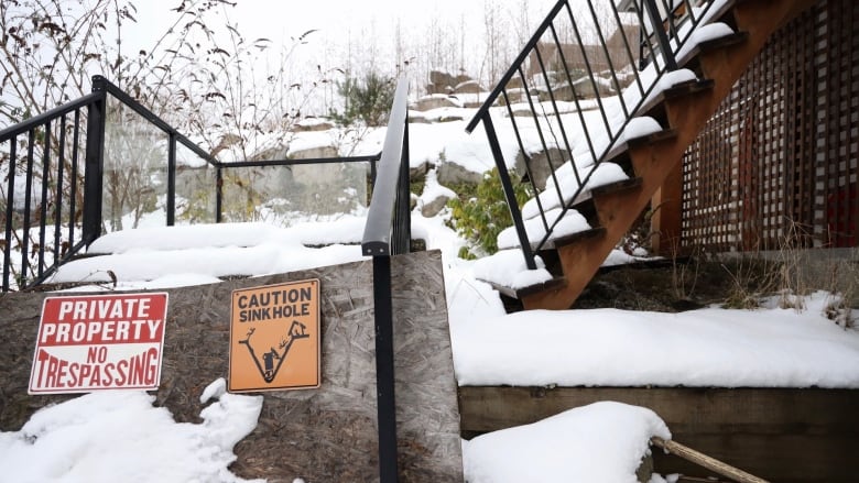 Broken stairs with two signs affixed. One says, 