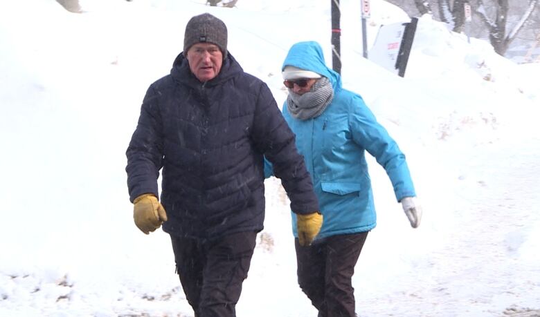 Two people walking in frigid winter weather. 