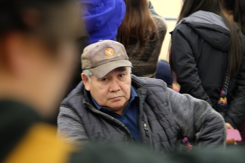 A man wearing a ball cap stares straight. 