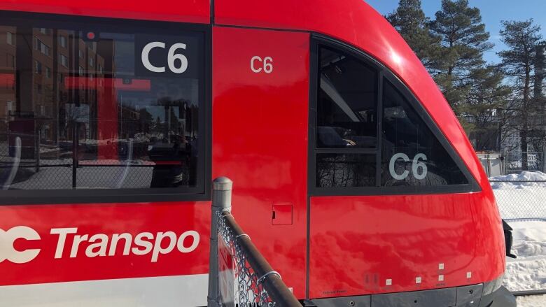 A red public transit train in winter.