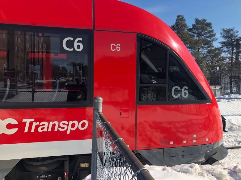 A red public transit train in winter.