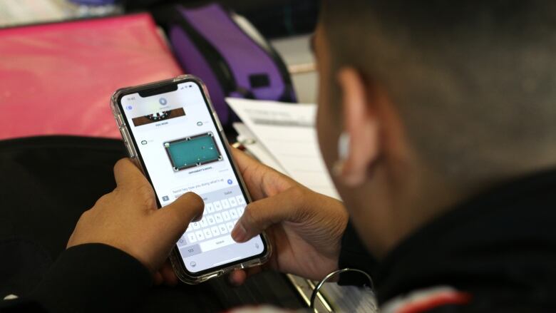 A high school student uses a cellphone in class.