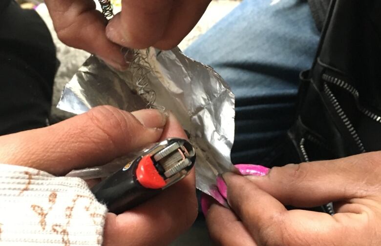 Close-up image of hands, foil and a lighter.