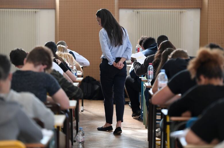 A teacher walks through rows of desks with students.