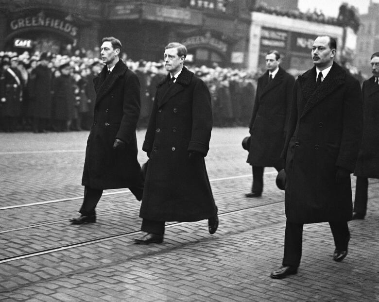 Men in coats walk down London street