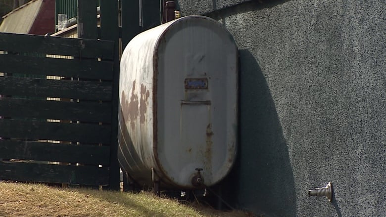 A home heating oil tank sits against a wall outside a residence.