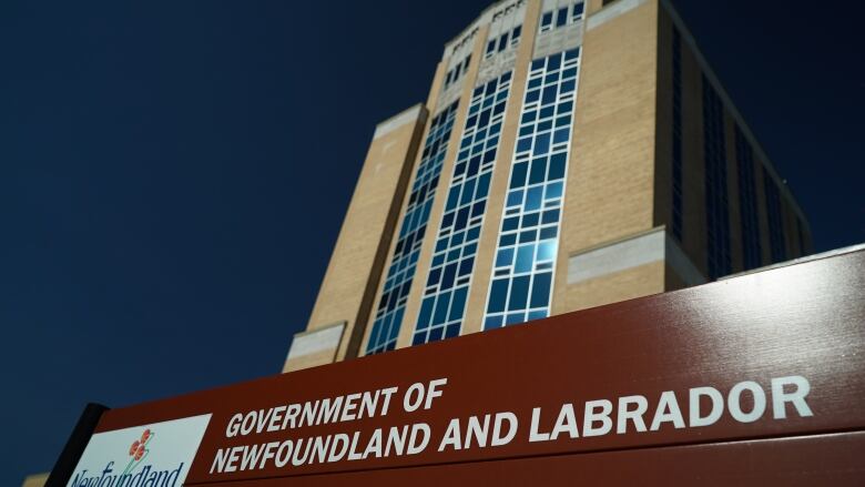 A sign is pictured in front of a building with a deep blue sky.