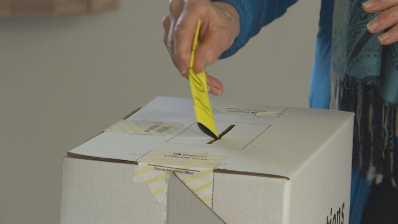 A person putting their ballot into a ballot box during the 2019 P.E.I. election.