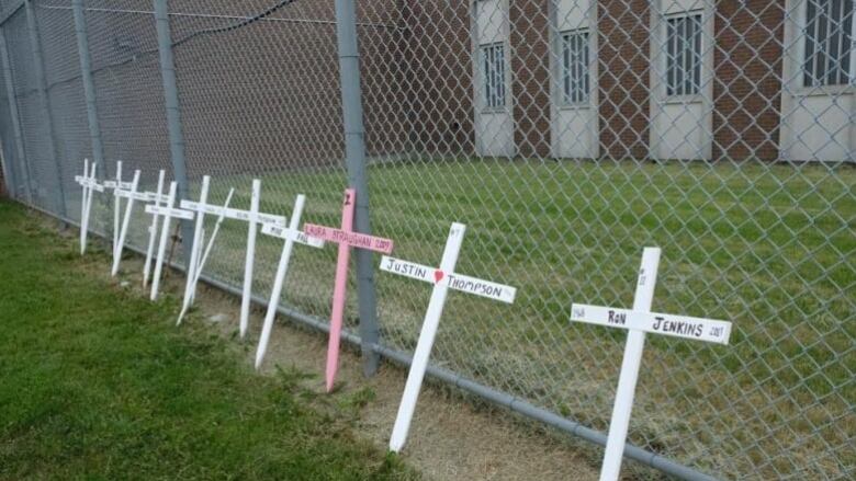 Crosses with the names of inmates who died rest against a fence at London's Elgin-Middlesex Detention Centre.