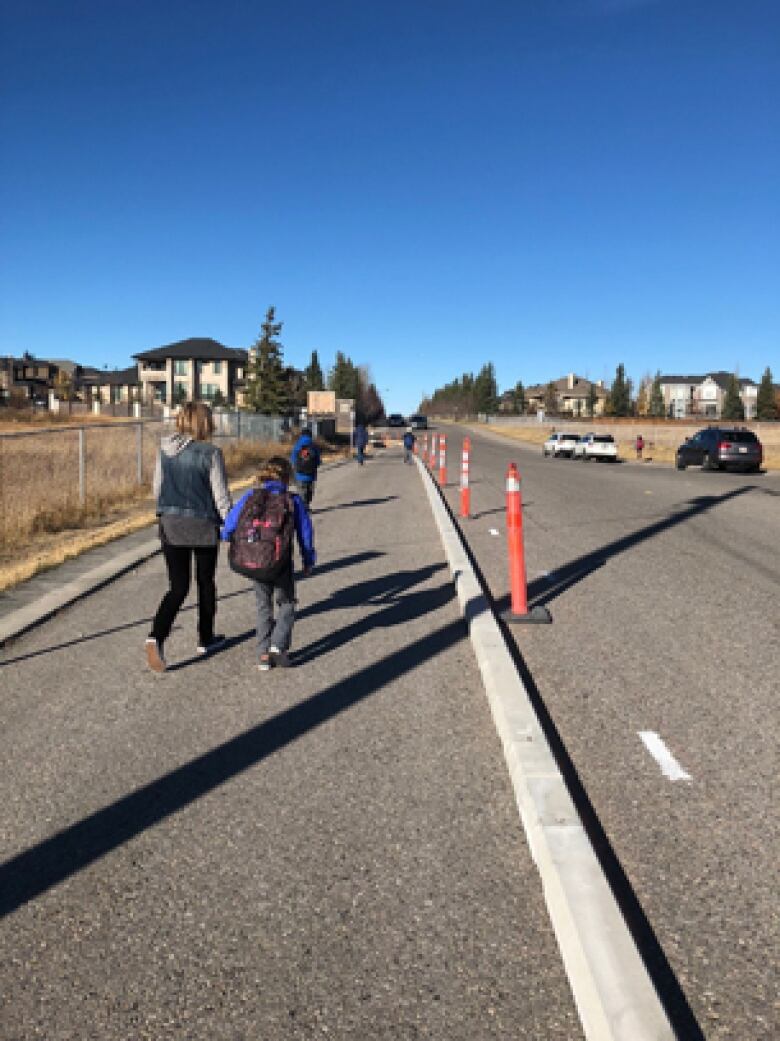 Pedestrians make their way along an adaptive sidewalk, marked by a low curb and markers.