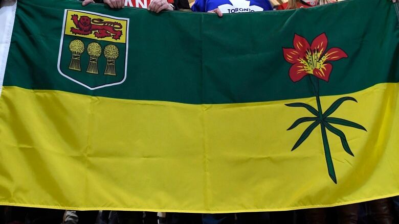 People in hockey jerseys holding the Saskatchewan flag