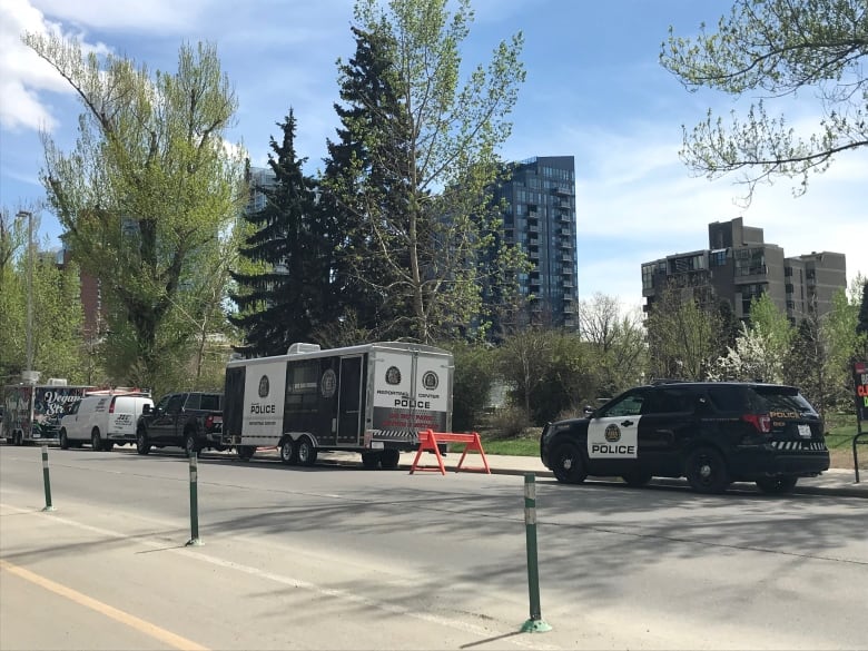 A police cruiser and trailer parked along the side of a street.