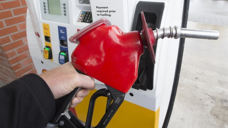 Close up of a hand holding the nozzle of a gas pump.