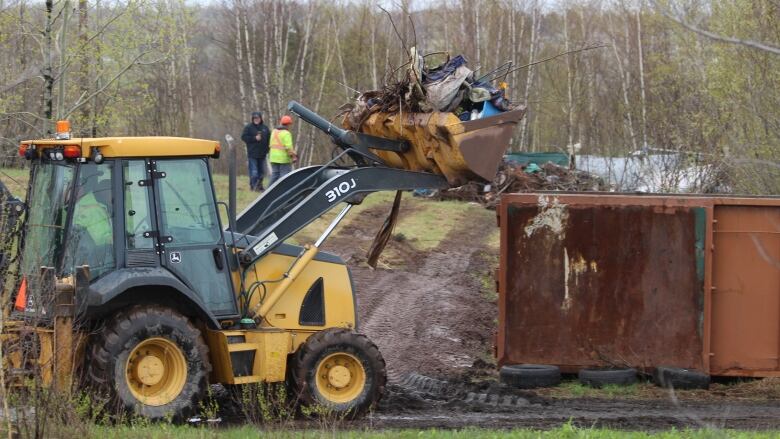 A bulldozer scooping material into a dumpster