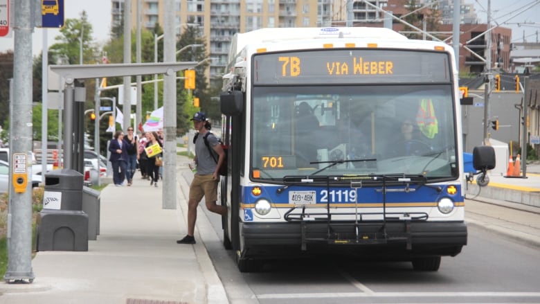 A man waring a cap gets off a bus.