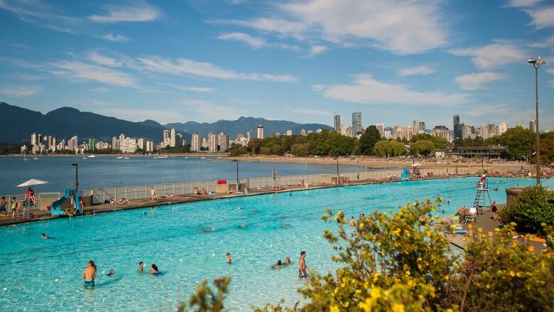 A large turquoise public pool overlooking the ocean, with the Vancouver skyline in the background. 