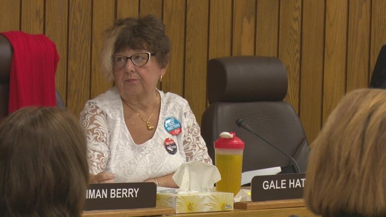 A woman sits in front of a microphone at a board meeting. 