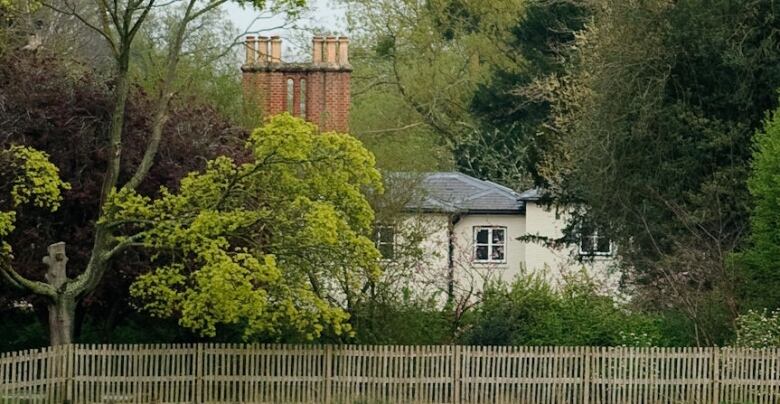 A large house is shown from a distance and behind some trees.