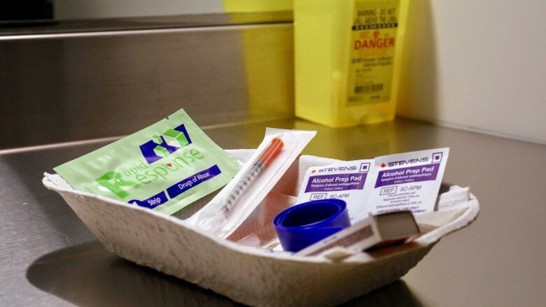 A dish of sterile needles, alcohol swabs, and drug test strips. 