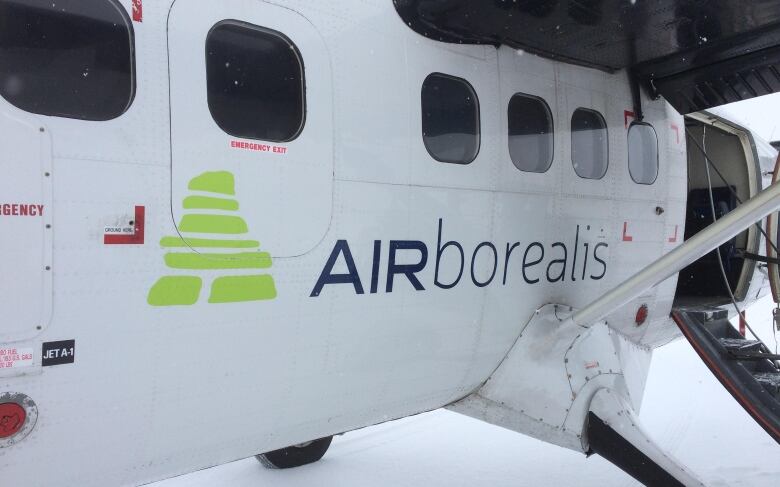 A close-up photo of an Air Borealis plane. The plane is white and has a logo of a lime green inukshuk (pile of stones.)