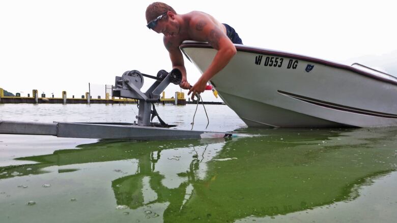 Ryan Atkins helps bring a boat ashore at South Bass Island State Park, Ohio, in Lake Erie, July 29, 2015. A algae bloom turned the water green at the park.