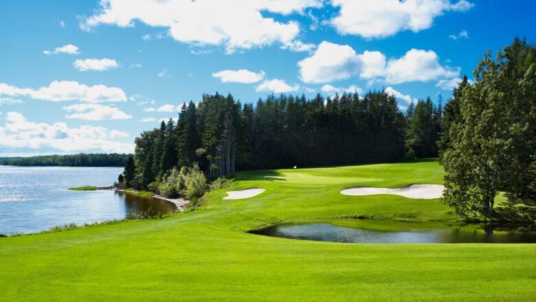 Bright blue skies over a brilliant green golf course by the side of the ocean.