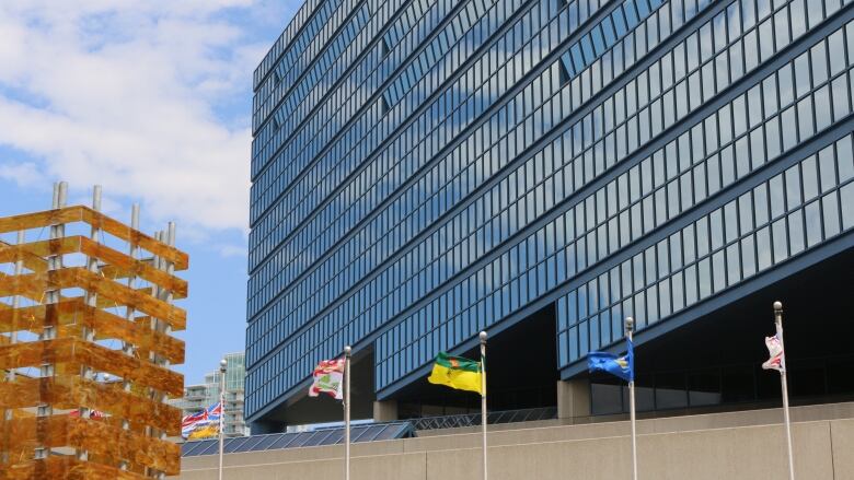 a glass building with many windows. various flags stand in front, blowing in the wind.