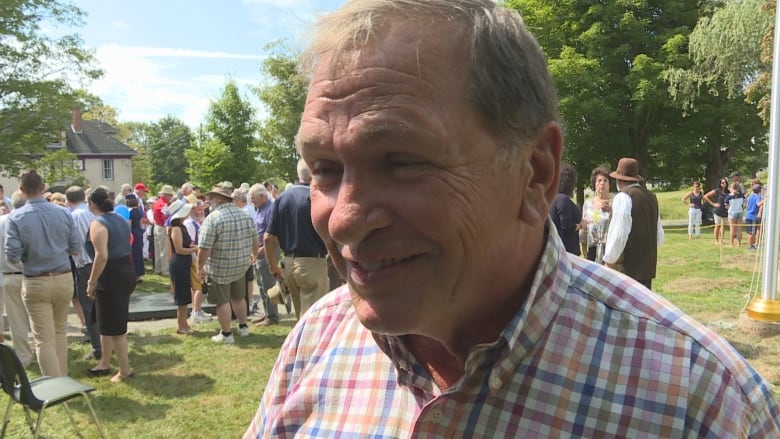 A smiling man in a crowd of people outside