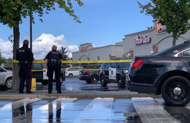 Two police officers and two police vehicles are outside a shopping mall.